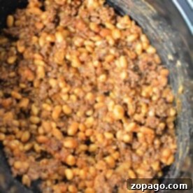 Close-up of baked beans with ground beef simmering to perfection in a slow cooker.