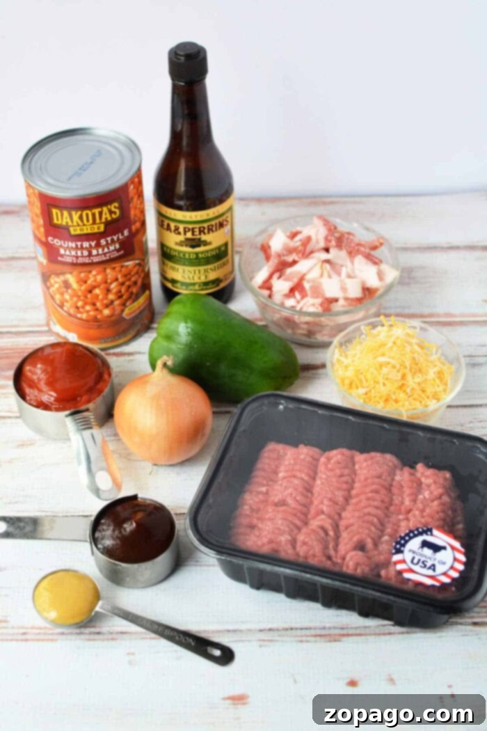 Savory Bean Medley 3 A variety of ingredients for a baked bean casserole are arranged on a white wooden surface, including a can of country-style baked beans, Worcestershire sauce, chopped bacon, a green bell pepper, shredded cheese, a ground meat package with an American flag sticker, an onion, measuring cups with sauce, and mustard.