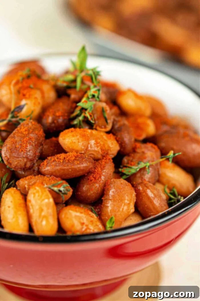 Unlock the Flavor of Tepary Beans 8 Close-up of seasoned baked tepary beans in a red bowl, garnished with sprigs of thyme.