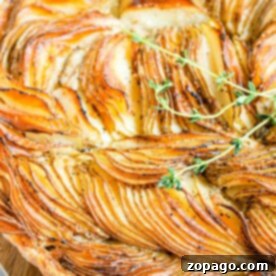Golden-brown potato tart galette garnished with fresh thyme on a wooden board.
