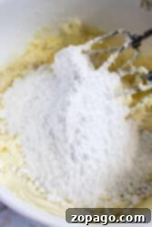 A mixer delicately blends flour and butter in a white bowl, setting the stage for the creation of a delightful dessert topped with creamy peppermint frosting.