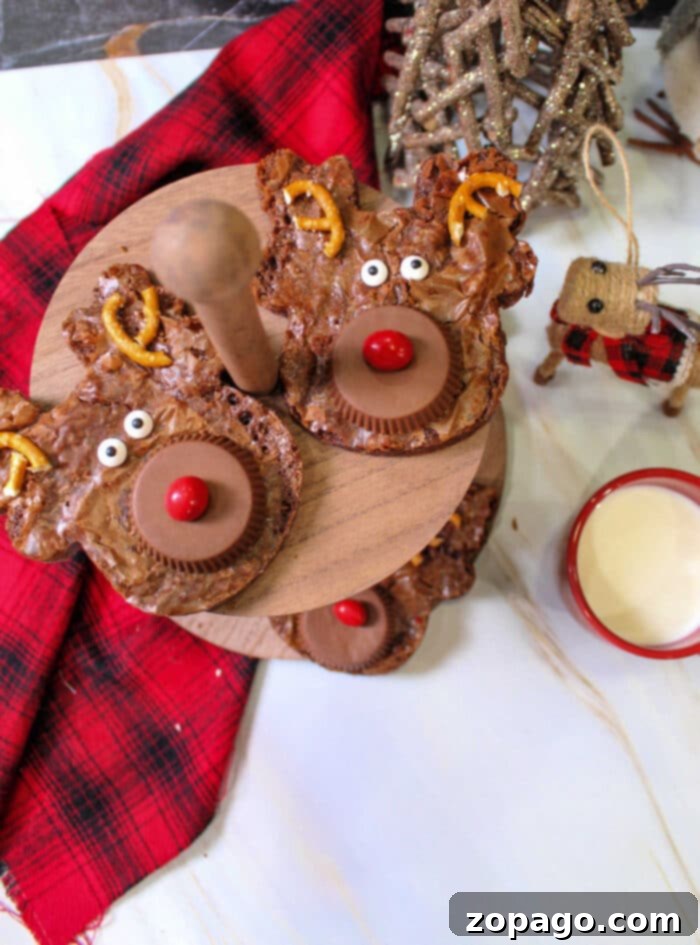 Santa's Favorite Brownies 6 An assortment of reindeer-themed brownies and other Christmas brownies displayed on a rustic wooden stand, accompanied by a red plaid cloth and a festive drink.
