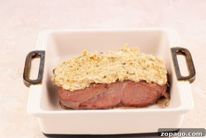 Crispy Parmesan Steak 4 steak with a mustard and Parmesan crust in a white baking dish with handles.