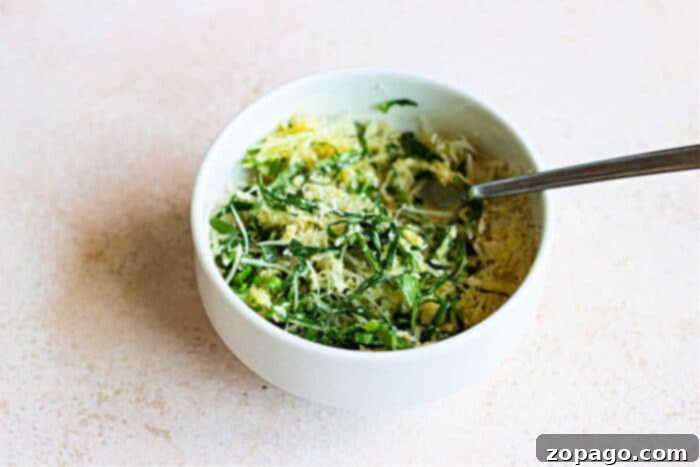 Crispy Herb Crusted Chicken 5 A bowl of vibrant greens, topped with slices of herbed crusted chicken, and a fork rests invitingly on the light surface.