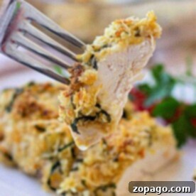 Crispy Herb Crusted Chicken 8 A fork holds a piece of herbed crusted chicken over a plate with garnished chicken.
