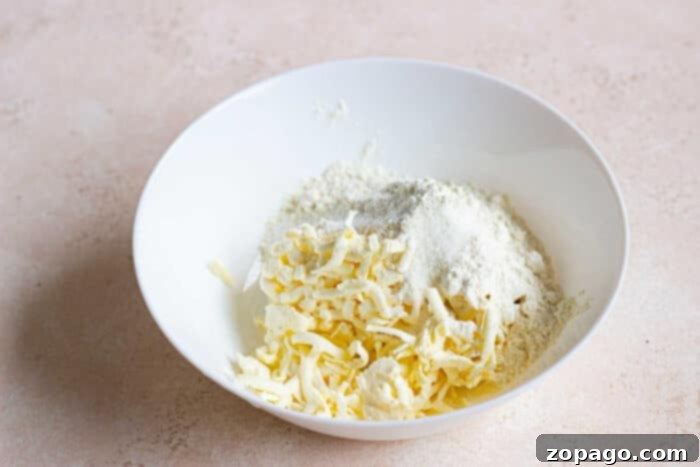 Flaky Sourdough Pie Crust 3 A white bowl brimming with shredded butter and flour rests on a light countertop, ready to craft the perfect sourdough pie crust.