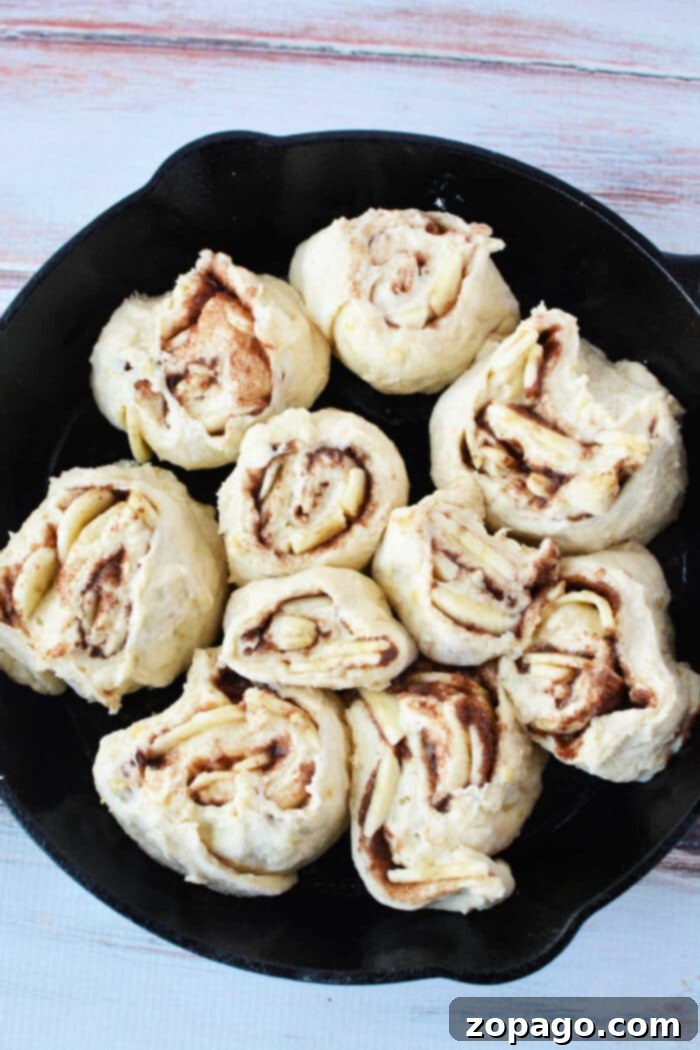Cinnamon Swirled Banana Bread Buns 7 Close-up of fluffy Cinnamon Rolls with Bananas and cream cheese frosting in a cast iron skillet.
