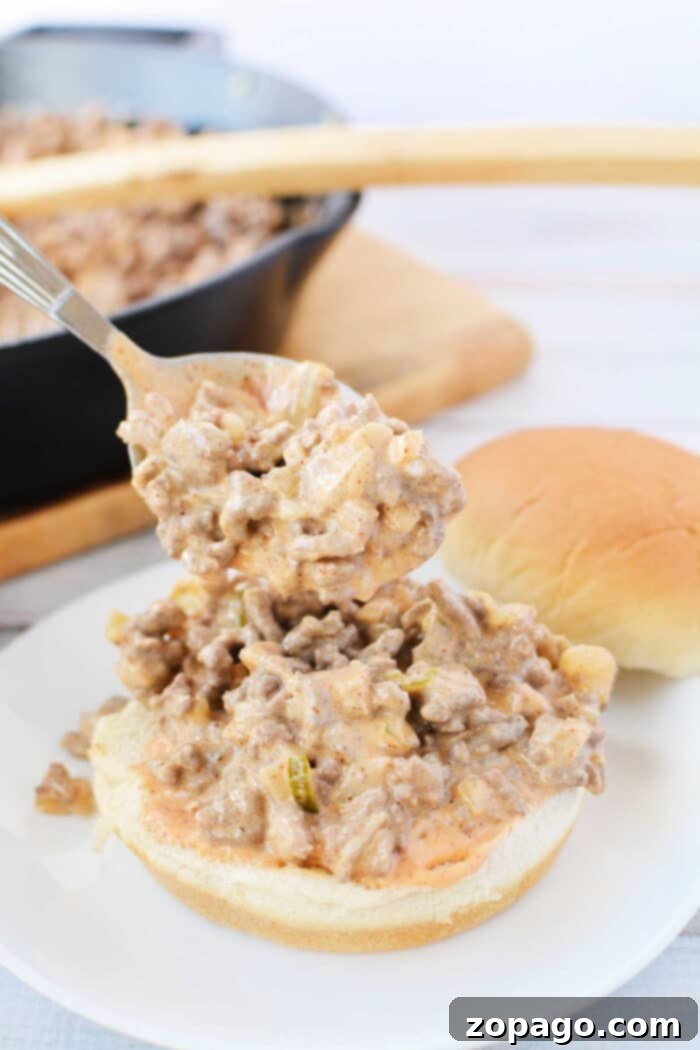 Big Mac Style Sloppy Joes 9 A spoon serving creamy Big Mac Sloppy Joes, with a skillet and more buns in the background.
