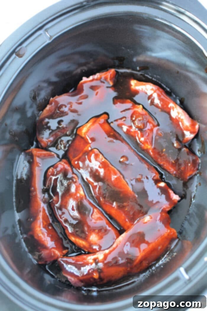 Fall Off The Bone Slow Cooker Country Ribs 6 Ingredients laid out for How to Cook Country Style Ribs, including spices, sauces, and raw boneless pork ribs.