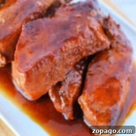 Slow cooker country-style ribs with liquid smoke and barbecue sauce on a white platter.