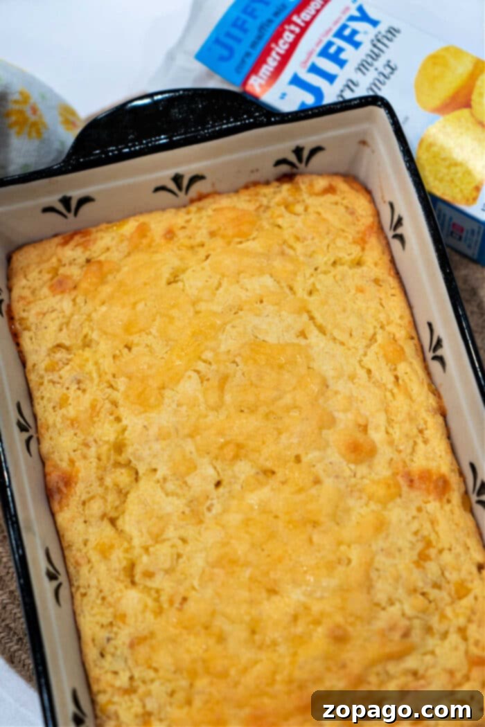 Effortless Cheesy Corn Bake 6 Baked cream corn pudding, featuring the Jiffy cornbread mix box in the background, highlighting the cream cheese corn casserole's main ingredient.