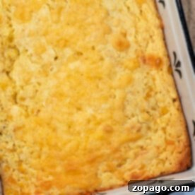 Golden cream corn casserole in a black and white baking dish, reminiscent of a delightful cream cheese corn casserole.