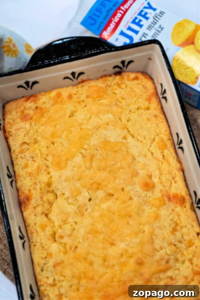 Effortless Cheesy Corn Bake 7 Jiffy corn casserole with a generous amount of cheese, steaming and ready to be served from a baking dish.