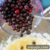 Pouring a mix of huckleberries into a bowl with batter, this easy muffin recipe promises delicious results.
