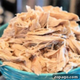 Shredded boiled chicken for dogs, piled generously in a blue bowl, offers a wholesome and delicious treat.