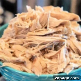 Gentle Boiled Chicken for Upset Dog Stomachs 5 Shredded boiled chicken for dogs, piled generously in a blue bowl, offers a wholesome and delicious treat.
