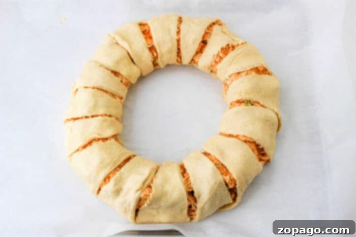 Step-by-step image of how to make a Crescent Roll Ring, folding the dough over the filling