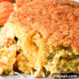Close-up of a portion of cornbread casserole with a golden crust, served alongside fresh broccoli and sliced carrots on a white plate.
