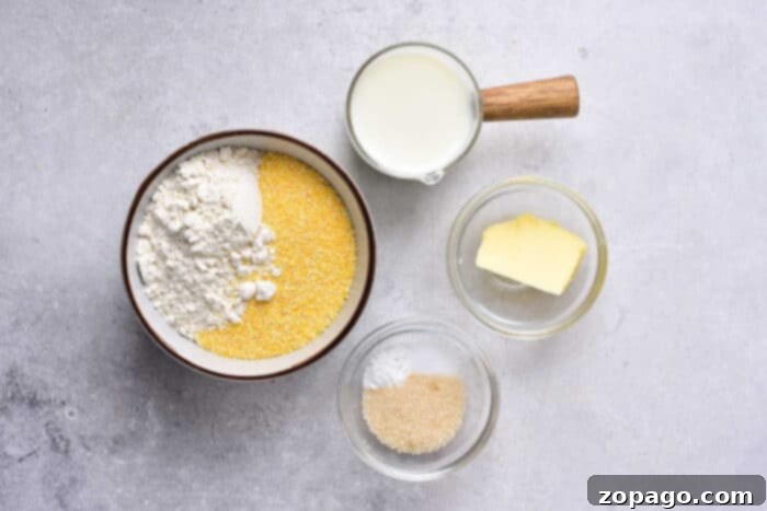 Hearty Chili Cornbread Casserole 4 A top-down view of various fresh ingredients laid out on a wooden surface, including cornmeal, flour, butter, egg, milk, sugar, and cheddar cheese, ready for homemade cornbread.