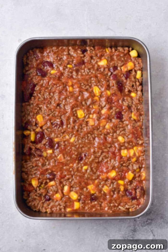 Hearty Chili Cornbread Casserole 5 A full baking dish of chili cornbread casserole, with the golden cornbread topping slightly cracked and revealing the rich chili beneath.