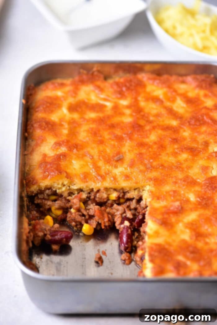 Hearty Chili Cornbread Casserole 7 A large, rustic baking dish filled with a golden-brown Jiffy chili cornbread casserole, ready to be served, highlighting its hearty and inviting appearance.