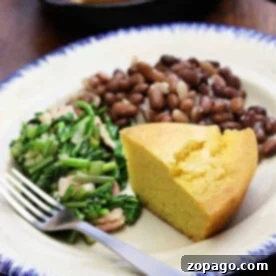 A plate featuring savory beans and cornbread alongside fresh greens, with a fork set neatly on the side.