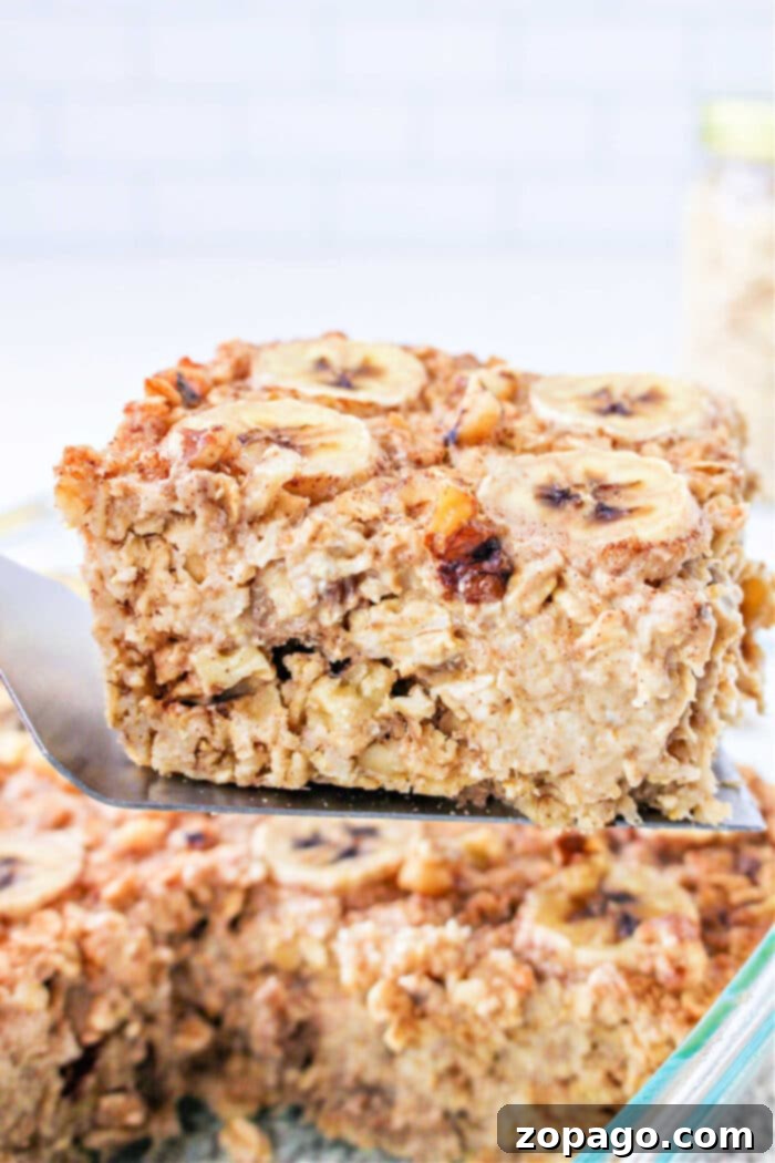 Banana Bread Oatmeal Bake 2 A spatula lifts a square of Banana baked Oatmeal, topped with fresh banana slices and crunchy nuts. Perfect healthy breakfast.