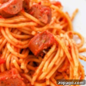 A plate of sausage spaghetti adorned with rich tomato sauce and perfectly sliced sausages.
