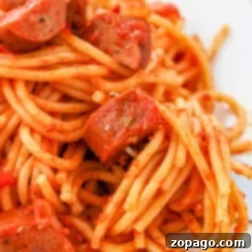 A beautifully presented plate of sausage spaghetti, adorned with rich tomato sauce and perfectly sliced sausages, ready for serving.