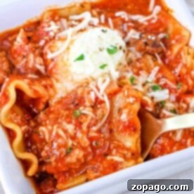 A close-up of one pot lasagna soup in a white dish, topped with melted cheese and herbs.