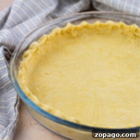 Flaky Dairy-Free Pie Crust 9 A dairy-free pie crust rests in a glass dish, perfectly prepared beside a blue and white striped cloth, ready for your favorite filling.