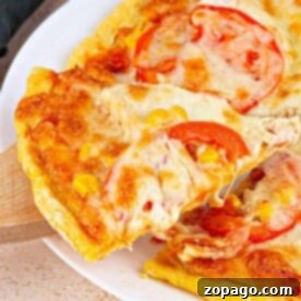Close-up of a cheesy pizza slice with tomatoes on a cornmeal pizza crust being lifted from the whole pie on a white plate.