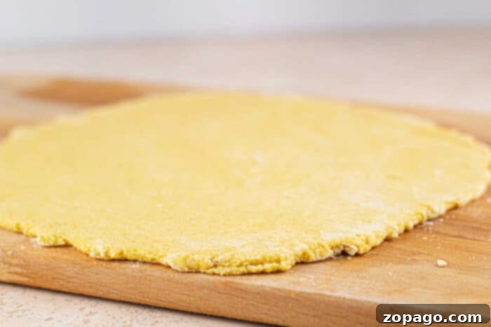 Crispy Cornmeal Pizza Crust 5 A freshly baked, golden brown cornbread pizza crust adorned with melted cheese and fresh basil, resting on a rustic wooden board.
