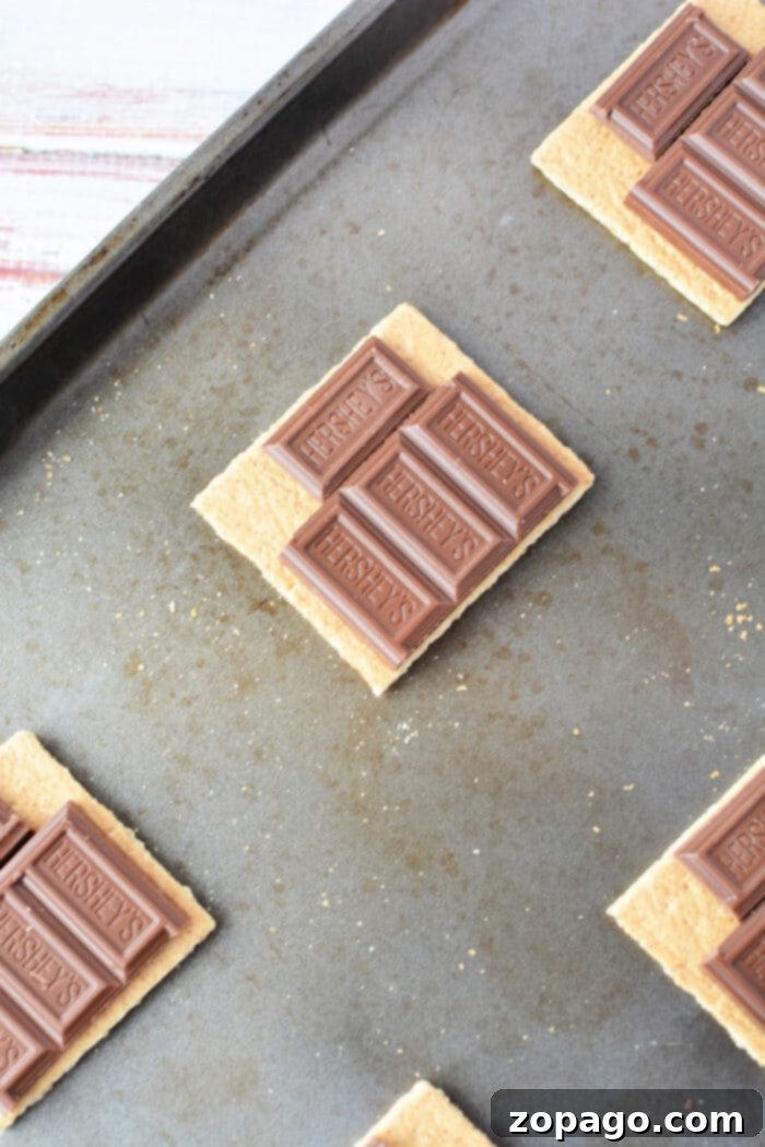 Baked S'mores Perfection 3 Assembling s'mores on a sheet pan before baking, showing graham crackers, chocolate, and marshmallows.