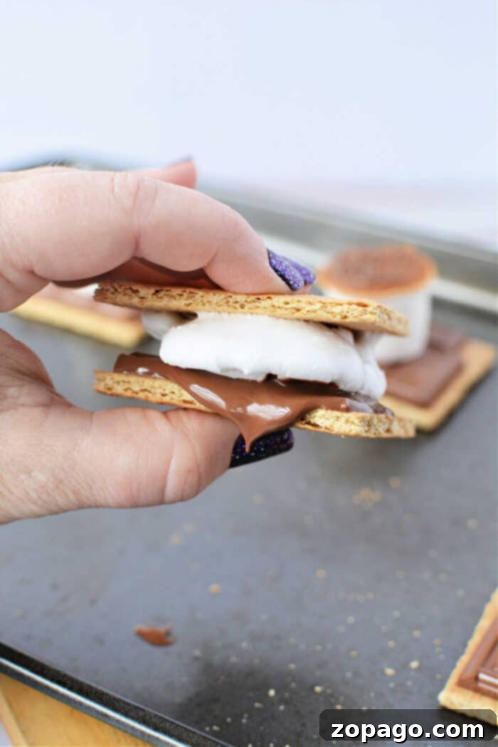 Baked S'mores Perfection 7 A perfectly assembled and toasted s'more resting on a white surface, showcasing its delicious layers.