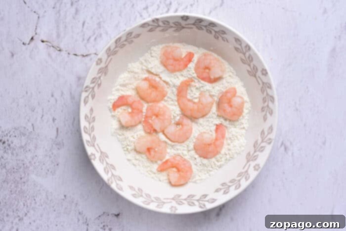 Golden Crispy Beer Shrimp 4 Uncooked shrimp in a bowl with flour, ready for beer battering