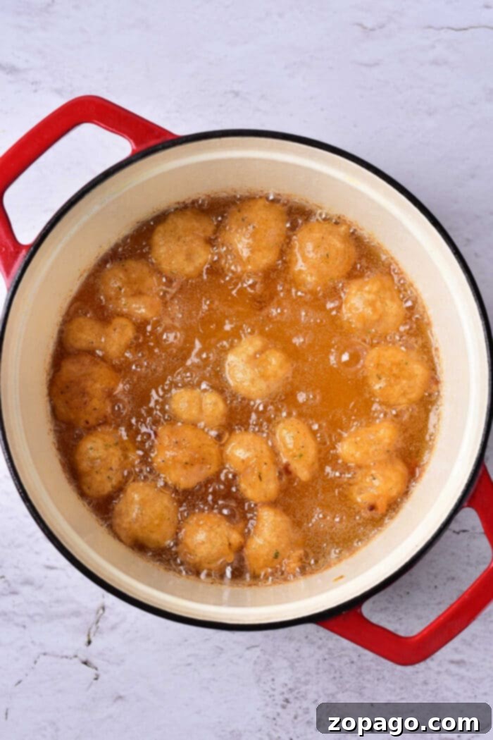 Golden Crispy Beer Shrimp 9 Golden-brown shrimp, crisp from their beer batter, sizzle in a red-handled pot filled with bubbling oil.