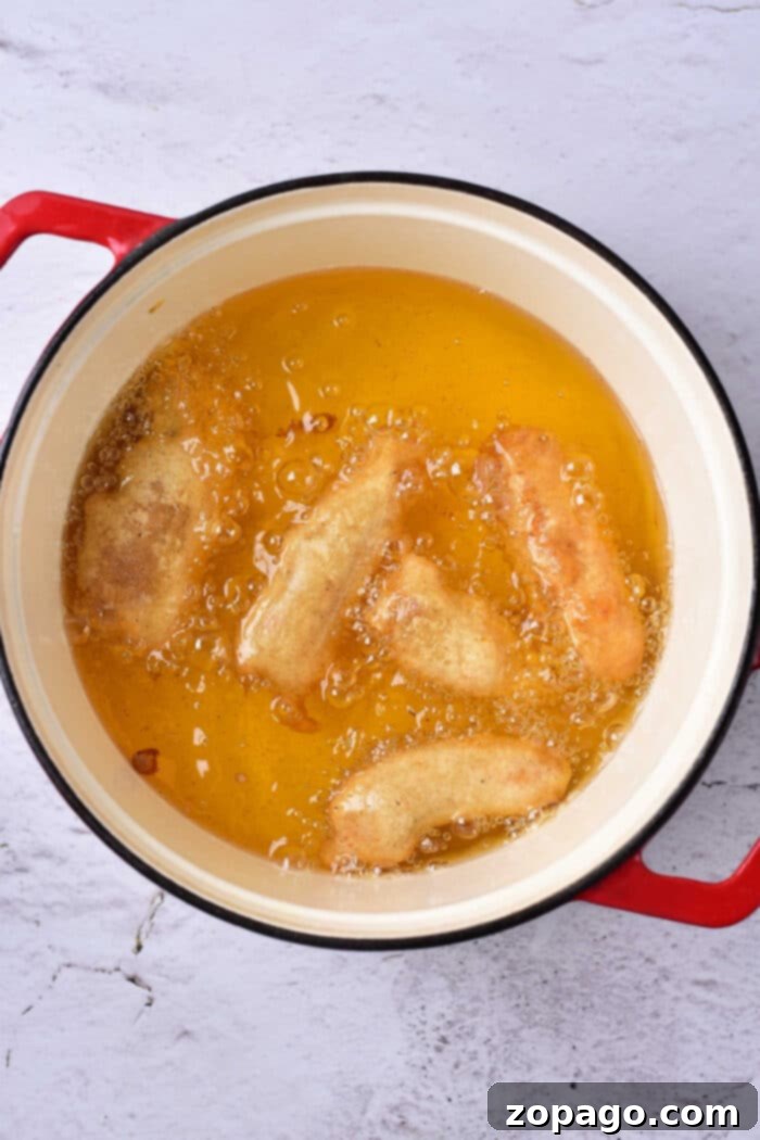 A basket full of perfectly cooked beer battered fish, garnished with lemon wedges.
