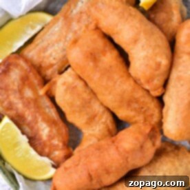 Golden-brown beer batter halibut pieces served in a basket with zesty lemon wedges.