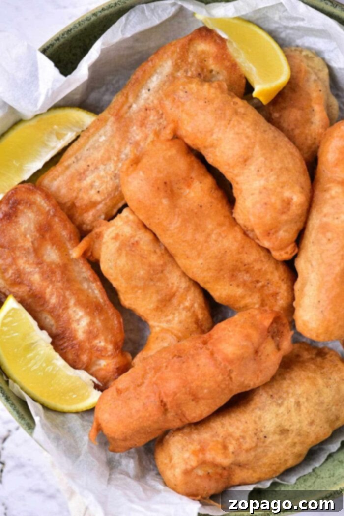 A serving of beer battered halibut with a side of coleslaw and a lemon wedge.