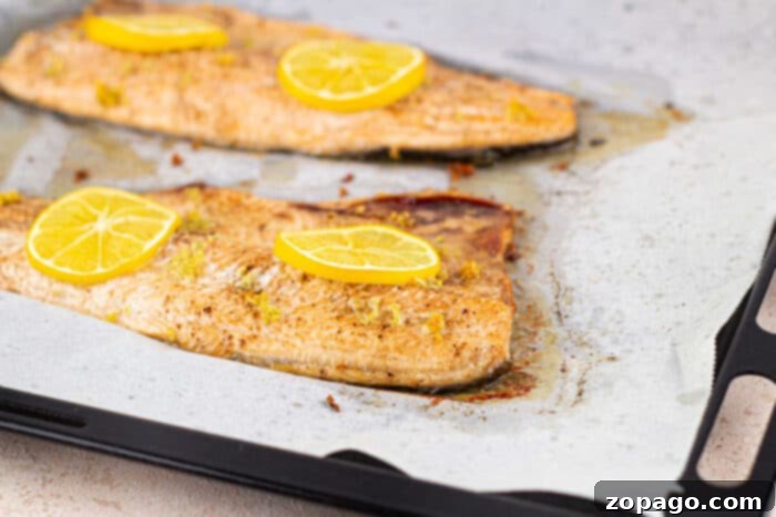 Oven-Baked Trout Perfection 6 Baked trout fillets with lemon and herbs on a baking sheet, ready to serve.