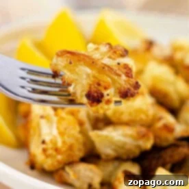 Golden Roasted Cauliflower at 400F 6 A fork holds a perfectly roasted piece of cauliflower, with lemon wedges elegantly arranged in the background on a pristine plate. Ever wondered how long to roast cauliflower at 400 degrees for this golden perfection?.