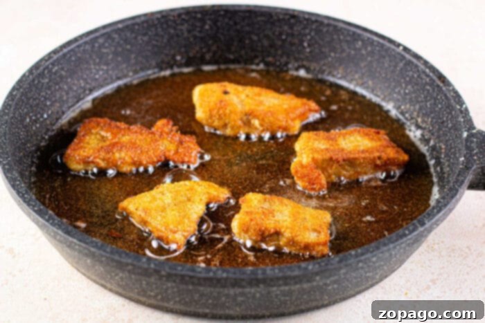 Crispy Fish Feast 7 Golden-brown fish fillets sizzling in a skillet, showcasing the perfect crispiness