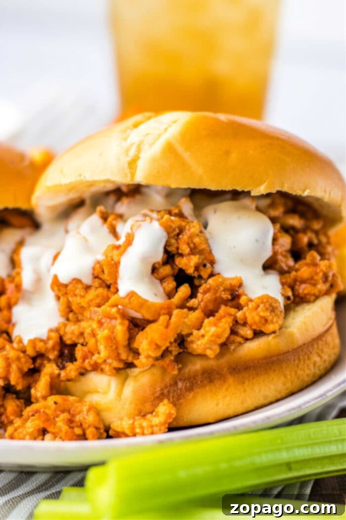 Hearty Chicken Sloppy Sandwiches 2 Close-up of a ground chicken sloppy joe sandwich with creamy sauce on a brioche bun, served with crisp celery sticks.