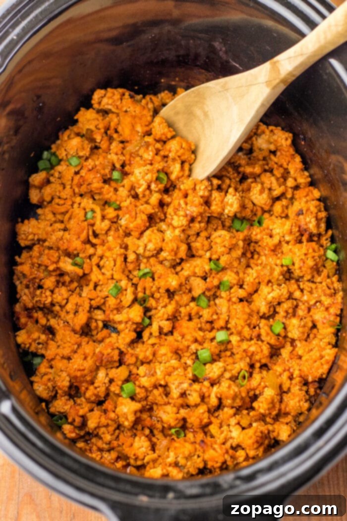 Hearty Chicken Sloppy Sandwiches 5 Seasoned ground turkey cooking in a slow cooker, transforming into a savory and delightful dish resembling Ground Chicken Sloppy Joes, garnished with fresh chopped green onions.