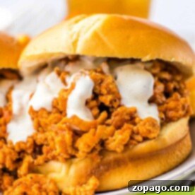 Hearty Chicken Sloppy Sandwiches 6 Close-up of a slow cooker ground chicken sloppy joe sandwich with creamy sauce on a bun, next to celery sticks.
