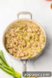 Hearty Chicken Sloppy Sandwiches 7 Ground chicken and diced green bell peppers sizzling in a skillet, creating a delicious aroma. Green onions are chopped and ready on the side.