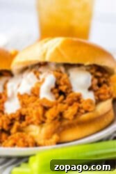 Hearty Chicken Sloppy Sandwiches 9 Close-up of a slow cooker ground chicken sloppy joe sandwich with creamy sauce on a bun, next to a few celery sticks.