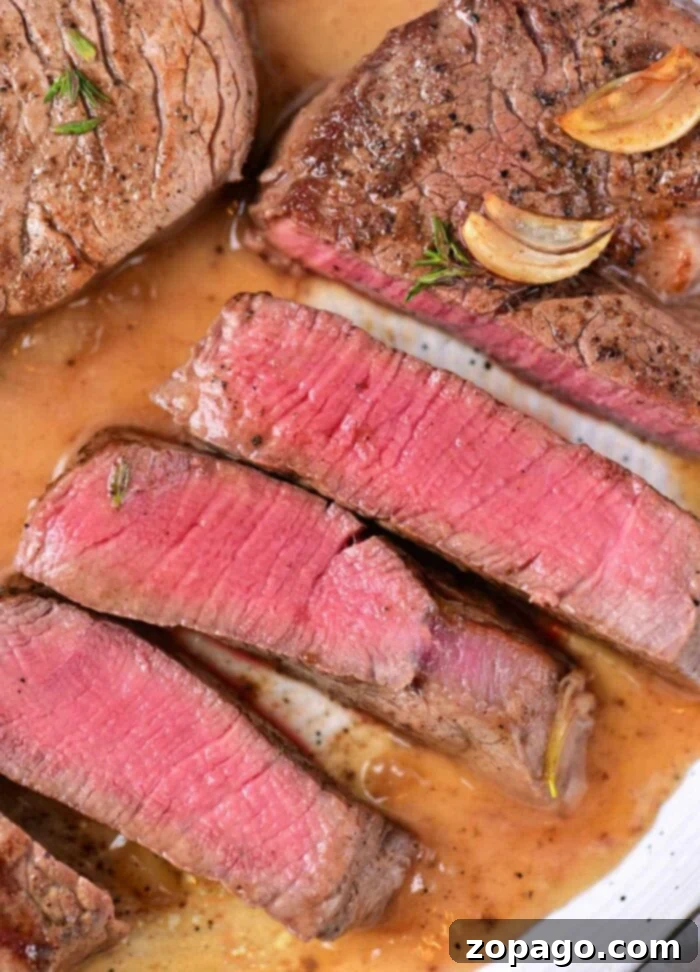 Perfectly Seared Beef Tenderloin Medallions 2 Two perfectly pan-seared beef tenderloin medallions with a golden-brown crust, garnished with herbs and ready to be enjoyed.