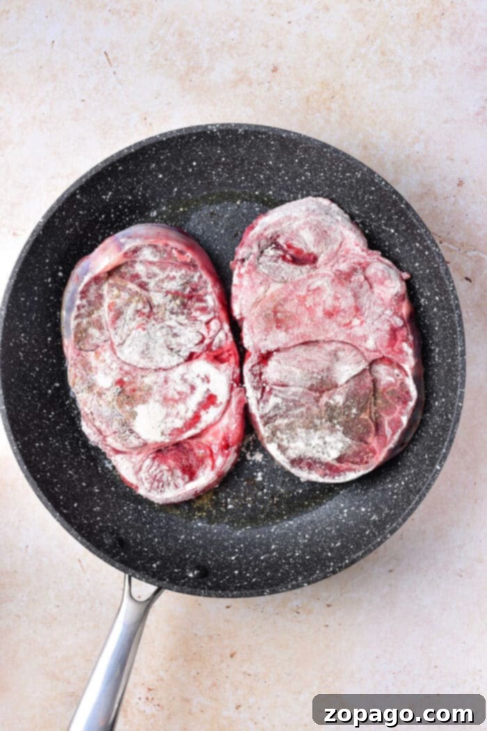 Slow-Braised Bone-In Beef Shank 4 Stove top Osso Buco simmering in a red Dutch oven, creating a rich and aromatic sauce, with steam rising.